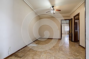 An empty room with a damaged oak parquet floor