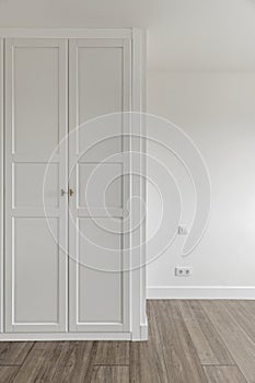 Empty room with fitted wardrobes with white wooden doors with access door and matching baseboards