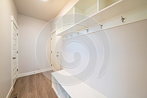 Empty room inside a home with wooden floor built in shelves hooks and two doors