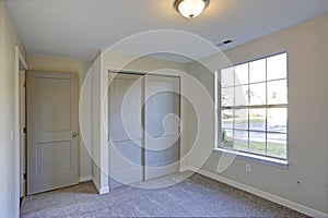 Empty room interior with beige walls and wall to wall carpet.