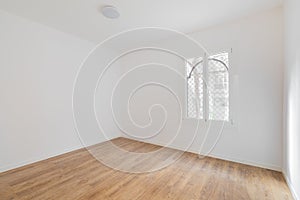 Empty room with laminate flooring, newly painted white walls and bright window. Repair and construction concept.
