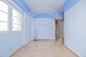 Empty room with light brown stoneware flooring, cast iron radiator