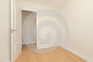 Empty room with light oak parquet flooring, plain white painted walls