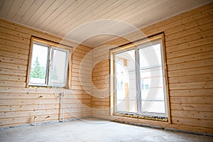 Empty room in a new wooden house, walls and ceiling colored with natural paint .