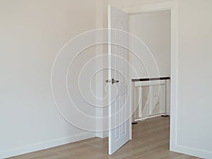 Empty room with open door and white interior wall background.