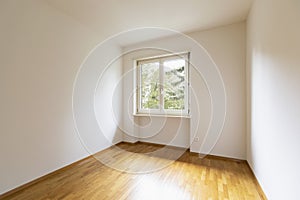 Empty room with parquet. Bright window with a view of nature