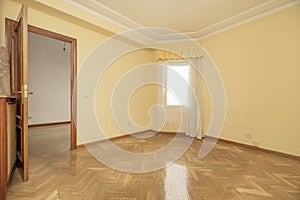 Empty room with shiny oak hardwood floor, matching woodwork, cream walls
