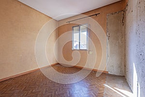 Empty room with sintasol floors, half-papered old walls and aluminum window