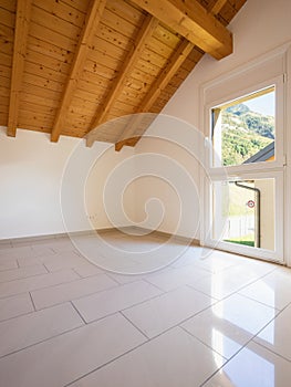 Empty room with a sloping roof and wooden beams