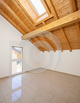 Empty room with a sloping roof and wooden beams