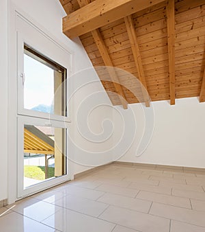 Empty room with a sloping roof and wooden beams