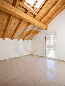 Empty room with a sloping roof and wooden beams