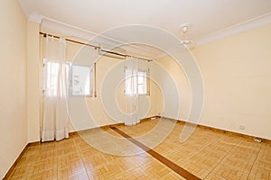 Empty room with two twin windows with white curtains and tiled floors