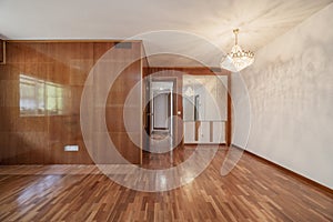 Empty room with varnished wood mural and mirrors, a crystal chandelier and matching parquet floors