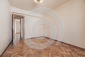 Empty room with varnished wooden doors, herringbone oak parquet floor