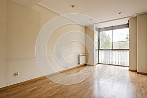 An empty room with walls full of marks from the old furniture and a bay window with curtains at the bottom