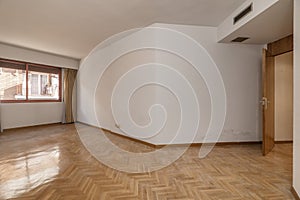 Empty room with white painted walls, French oak parquet wooden floor placed in a herringbone pattern with matching doors and