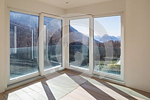 Empty room with white walls and windows overlooking the mountains photo