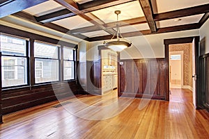 Empty room with wood paneled walls and coffered ceiling.
