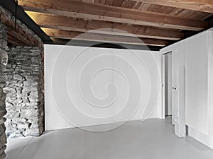 an empty room with wooden beamed ceiling and resin floor