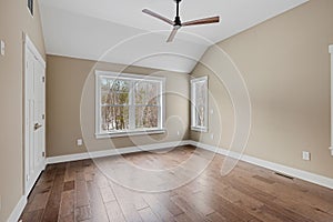 Empty room with wooden floors, a ceiling fan and white brown walls