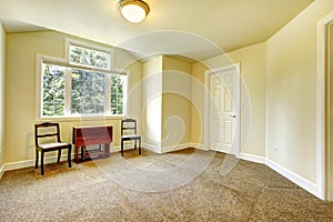 Empty room with yellow walls and brown carpet.