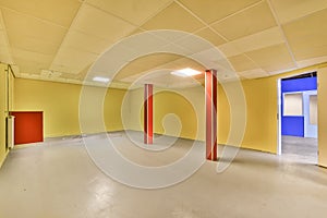 an empty room with yellow walls and red pillars