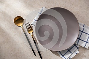 Empty round light brown plate with cutlery placed on the side Empty dish on a napkin with space for your design with from natural