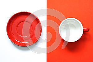 empty round red ceramic mug and red round ceramic saucer  placed on two tone colour of white and red background.