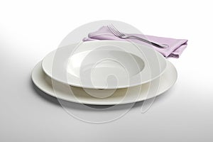 Empty round white plate and bowl with napkin and fork