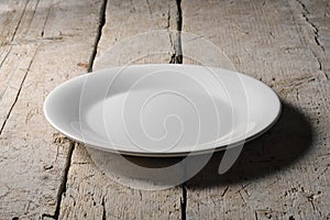 Empty white round plate on rough wooden table