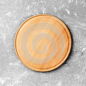 Empty round wooden dish on table over gray cement wall background, for product display montage