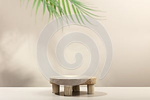Empty round wooden podium for product presentation and palm leaves on beige background for cosmetic product mockup