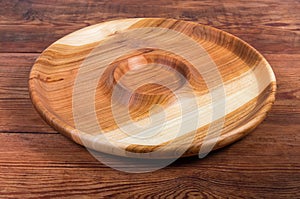 Empty round wooden serving dish with sauce boat in center