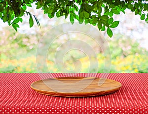 Empty round wooden tray on red polka dot tablecloth over blur tr