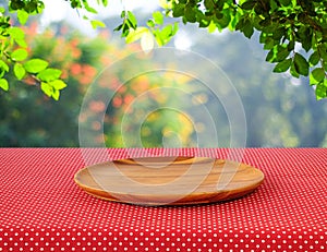 Empty round wooden tray on red polka dot tablecloth over blur tr