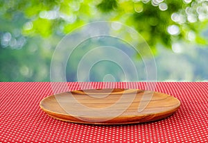 Empty round wooden tray on red polka dot tablecloth over blur tr
