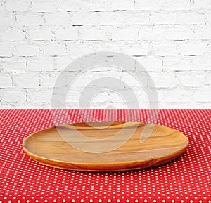 Empty round wooden tray on red polka dot tablecloth over white b