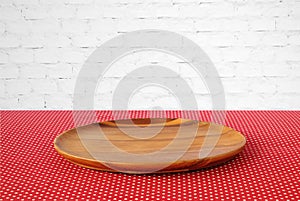Empty round wooden tray on red polka dot tablecloth over white b