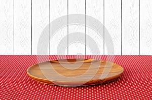 Empty round wooden tray on red polka dot tablecloth over white w