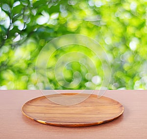 Empty round wooden tray on table over blur tree background