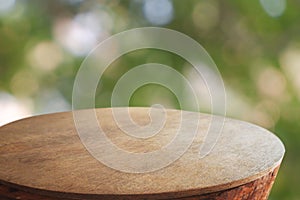 Empty rounded wooden table in front of abstract blurred green bokeh light of garden and nature light background. For montage