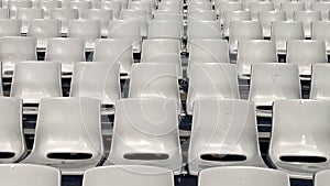 Empty rows of plastic seats or chairs in the stands or stadium. Lots of empty seats for spectators in the stands for