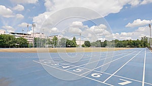 Empty running path in the blue sky and fluffy clouds background. nobody in the school in summer break. sport and outdoor activity