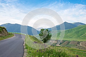 Empty rural road in mountains with morning blue cloudy sky