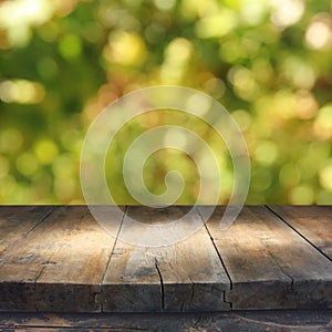 Empty rustic table in front of green spring abstract bokeh background. product display and picnic concept.