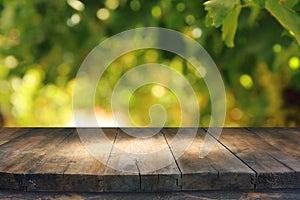 Empty rustic table in front of green spring abstract bokeh background. product display and picnic concept. photo