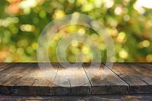 Empty rustic table in front of green spring abstract bokeh background. product display and picnic concept.