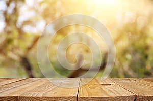 Empty rustic table in front of green spring abstract bokeh background. product display and picnic concept. photo