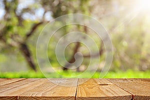 Empty rustic table in front of green spring abstract bokeh background. product display and picnic concept.